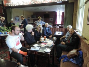 Lots of people chatting over tea, coffee and cake whilst looking at plants and books in the swap.