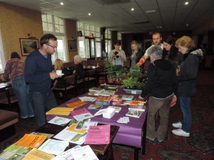 Leaflets and books and plants on the table. Local people chatting and getting to know each other.
